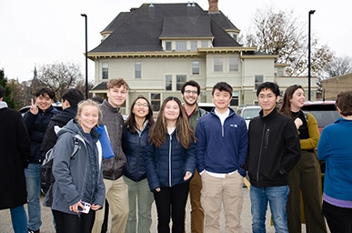 12 students in front of older home in parking lot