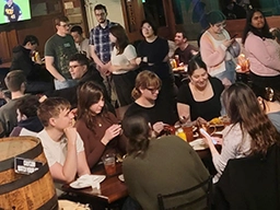 A group of people dining at tables in a restaurant, engaged in conversation and enjoying their meals.