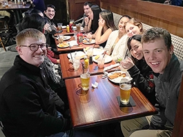 group of students sitting at a long table at pub with meals