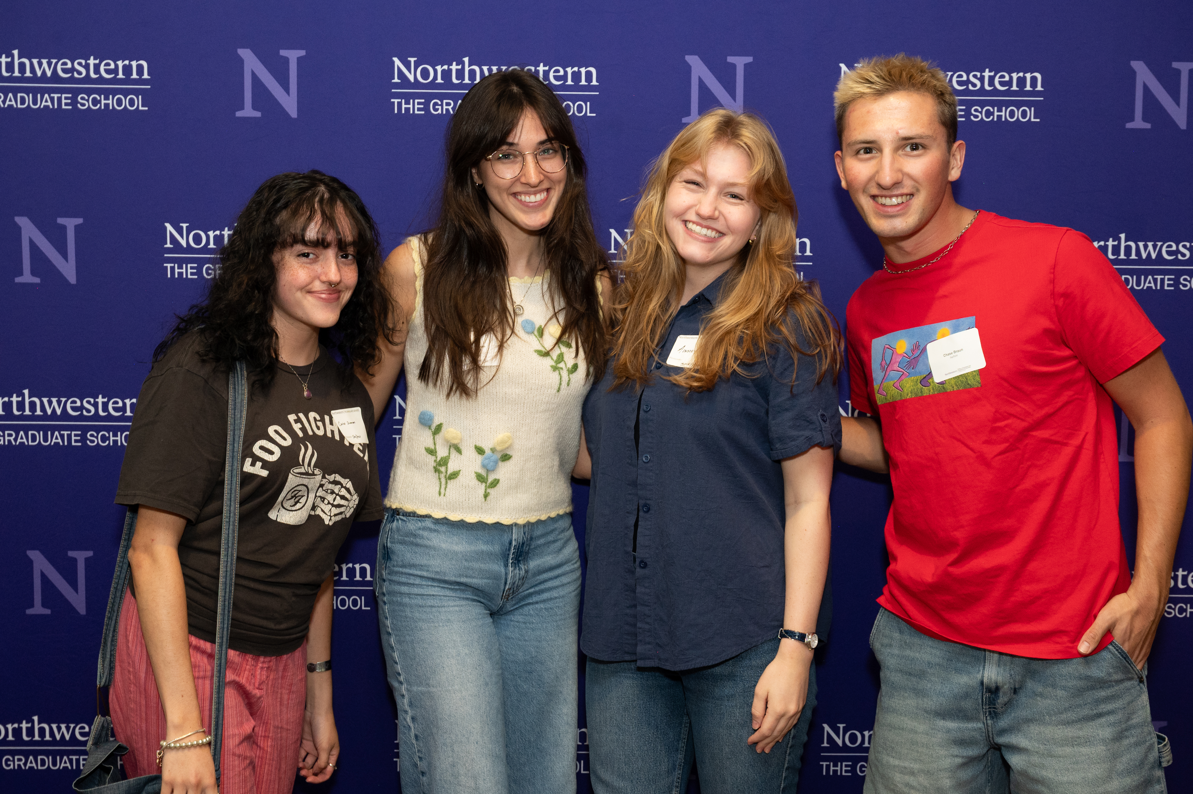 Four students posing in front of the Northwestern banner.