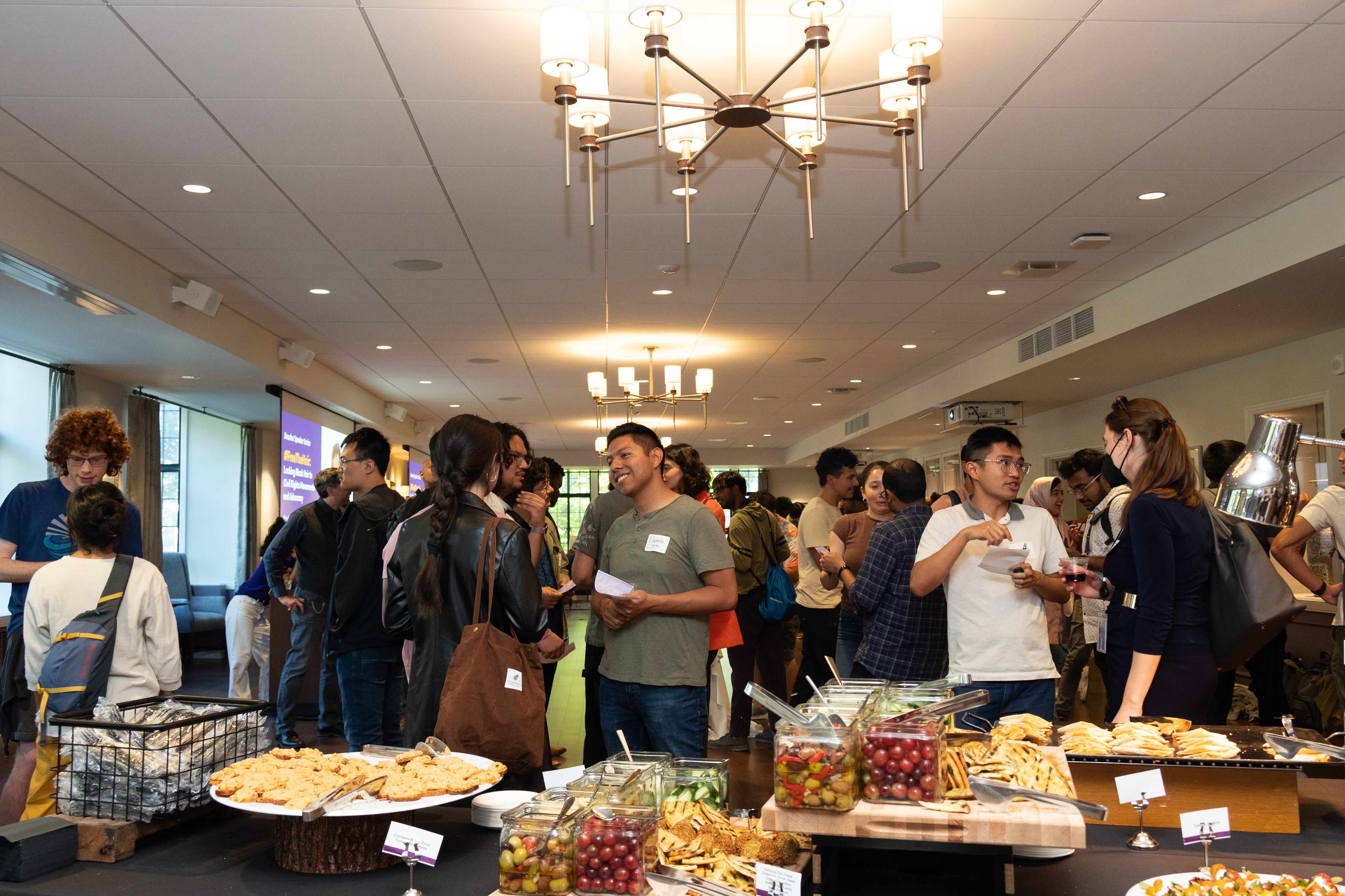 A large buffet of food with people talking in the background.
